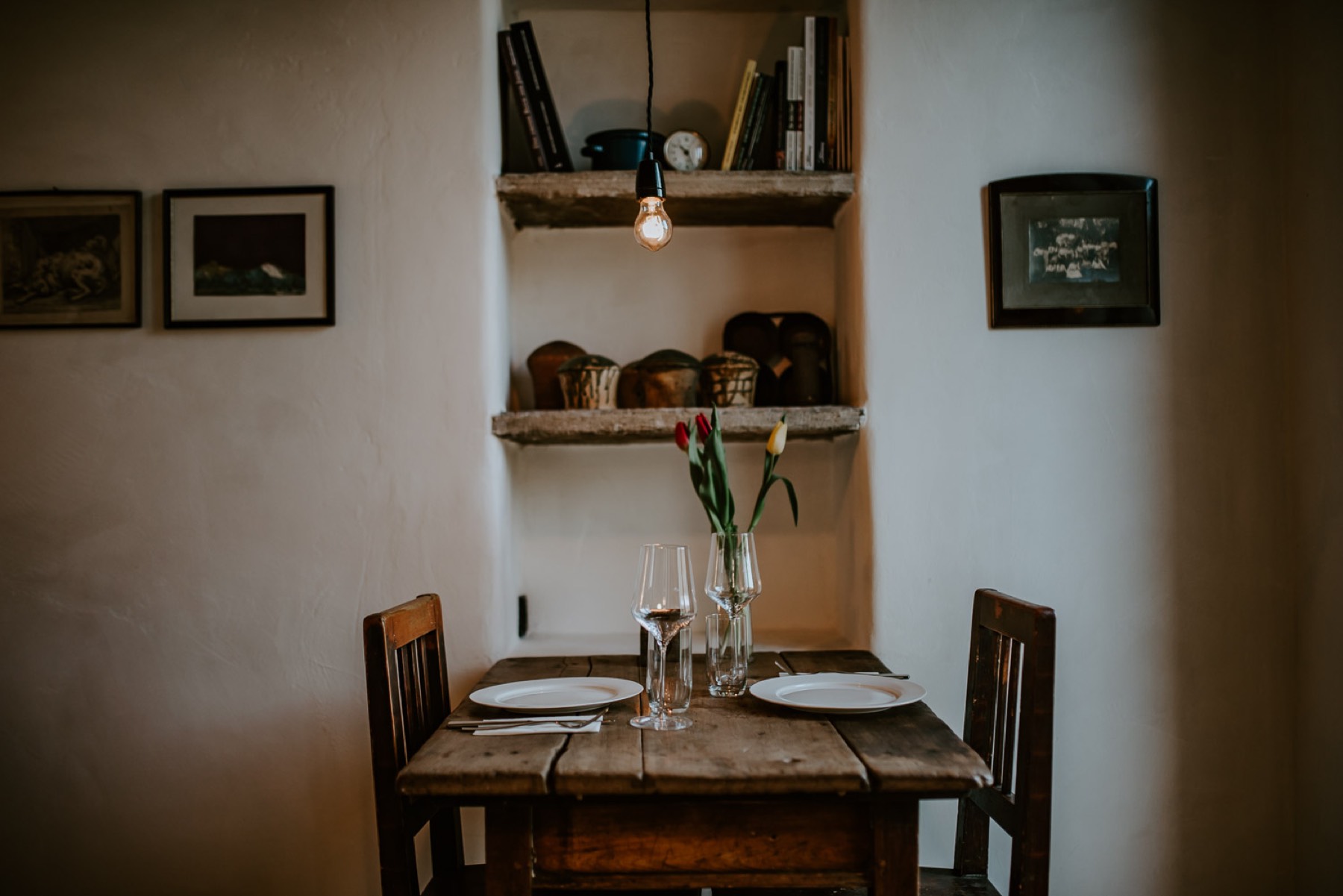 A dining room with a set wooden table and framed pictures